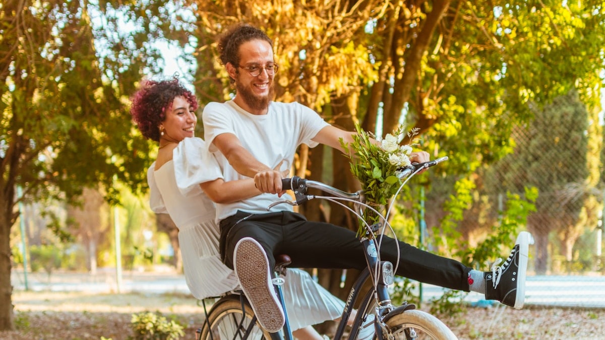 a man and a woman riding a bicycle in a park